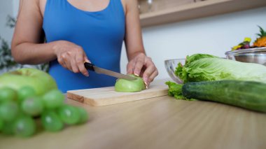 Mutfakta yeşil elma dilimleyen bir insan, sağlığını ve besleyici yemek hazırlıklarını teşvik ediyor..