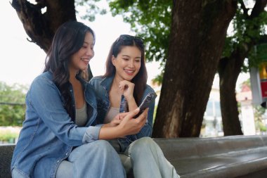 İki arkadaş parkta bir bankta oturup kahvelerini yudumluyor ve akıllı bir telefonla yakınlaşıyorlar. Kefaletlerini ve boş zamanlarını vurguluyorlar..