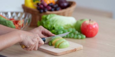 Bir insan ahşap kesim tahtasında taze elmaları ustalıkla dilimleyip sağlıklı beslenmeyi ve sağlıklı beslenmeyi teşvik eder..