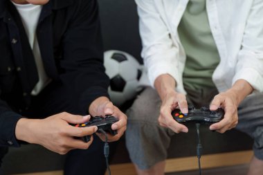 Oyun oynayan iki aile üyesi, her biri bir kontrolör tutuyor, eğlenceli ve rekabetçi bir anın tadını çıkarıyorlar..