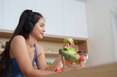 Bir kadın bir kase sebzenin tadını çıkarırken elmayı inceler, sağlıklı beslenme ve sağlıklı beslenme alışkanlıkları gösterir..