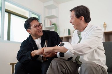 Genç bir adam ve yaşlı bir adam neşeli bir anı paylaşıyor, gülüyor ve futboldan zevk alıyor, aile bağlantısını ve mutluluğu vurguluyor..