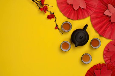 Çin Yeni Yılı için, neşe ve refahı sembolize eden, çay, kırmızı yelpazeler ve şenlikli süslemeler sunan neşeli bir üst manzara..