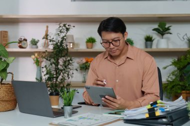 Bir işadamı, modern bir ofiste dijital araçların önemini vurgulayarak proje yönetimi için bir tablet hazırlıyor..