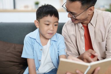 Bir baba ve oğul bir okuma anını paylaşıyor, rahat bir ev ortamında öğrenmeyi ve bağlanmayı teşvik ediyor..