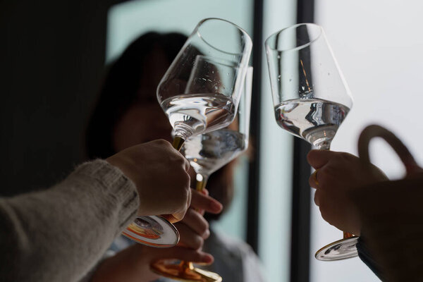 A close-up of friends toasting with glasses, symbolizing joy and camaraderie at a lively party.