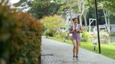 Spor giysiler giymiş kadın koşucu sabah parkta koşuyor. Etkin sabah.