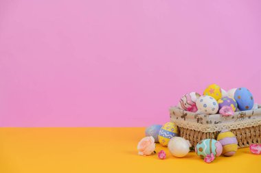 Dekoratif bir sepete yerleştirilmiş pastel Paskalya yumurtaları. Narin çiçeklerle tamamlanmış. Bahar şenlikleri için ideal..