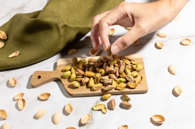 Kadın eli mutfak tezgahındaki tahta tahtadan fıstık topluyor. Yüksek kalite fotoğraf