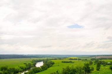 Nehir ve tarlaların üzerindeki bulutlu gökyüzü, yaz.