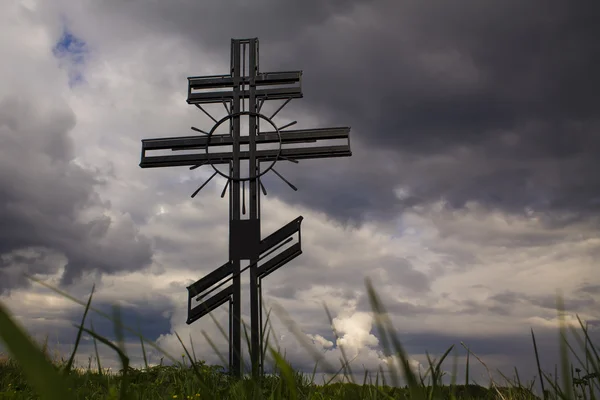 Cruz cristiana conmemorativa sobre un fondo de cielo y hierba — Foto de Stock