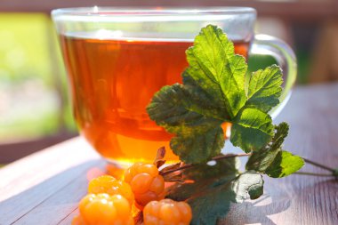 Fincan çay ve bir bahar dalı cloudberry çilek ve yaprakları