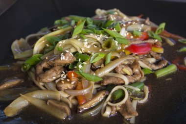 Deniz kenarı bir kafede et ve sebze ve yeşil soğan ile Çin eriştesi