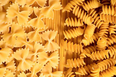 Çiğ farfalle ve fusilli makarna yığınının yakın çekimi. İtalyan makarnası, yukarıdan görünüyor..