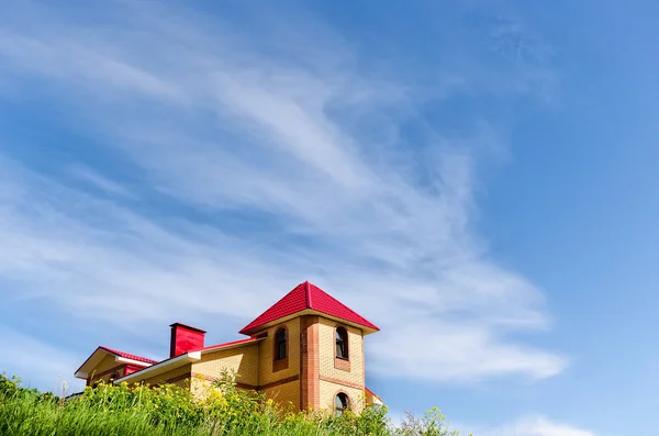 Tepenin üstüne tuğla ev. Gökyüzü arka plan