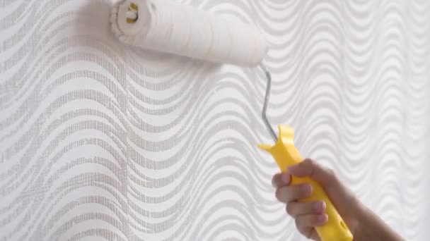 4k. Primo piano delle mani della donna utilizzando rullo di vernice durante la pittura carta da parati colore bianco, lavorando all'interno. — Video Stock