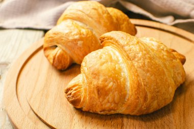 Ahşap kesme tahtasının üstünde taze pişmiş kruvasanlar, üst manzara. Seçici odak.