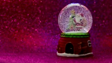 Kar ve Noel Baba 'nın pembe arkaplanda olduğu bir Noel kartopu.