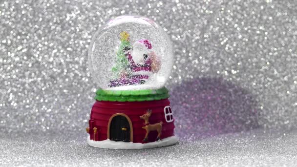 Χριστουγεννιάτικη μπάλα με χιόνι και Σάντα σε ασημί φόντο glitter. — Αρχείο Βίντεο