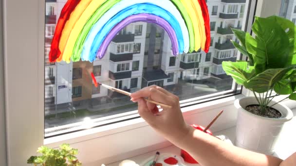 Meisje schilderen regenboog op venster tijdens quarantaine thuis. — Stockvideo