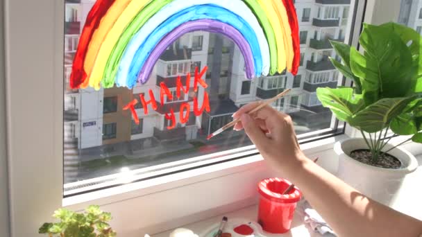 Girl painting rainbow on window during quarantine at home. — Stock Video