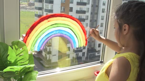Dívka malování duha na okně během karantény doma. — Stock video