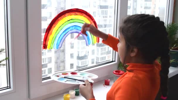 Ragazza pittura arcobaleno sulla finestra durante la quarantena a casa. — Video Stock