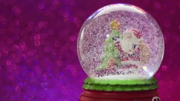 Kerstbal met sneeuw op roze glitter achtergrond. — Stockvideo