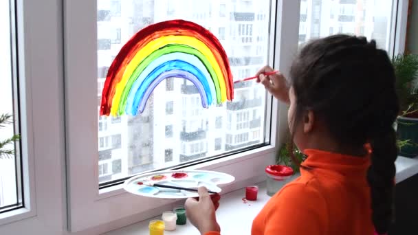 Ragazza pittura arcobaleno sulla finestra durante la quarantena a casa. — Video Stock