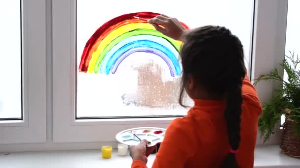 Ragazza pittura arcobaleno sulla finestra durante la quarantena a casa. — Video Stock