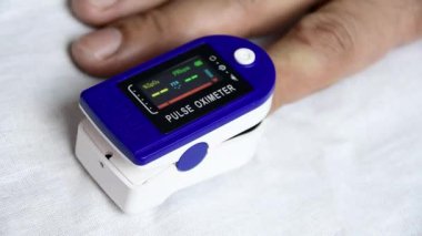 Bir adam parmağına nabız oksimetresi takmış ve kalp atışlarını ve kanındaki oksijen miktarını kontrol etmiş. Koronavirüs enfeksiyonu kapmaktan korkan COVID 19.