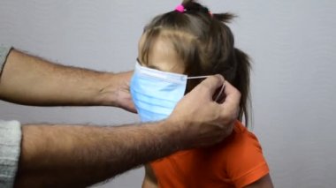 Babam Covid-19 salgını sırasında koyu kahverengi gözlü bir kıza mediacl maske takıyor. Şirin Hintli çocuk cerrahi maske takıyor.