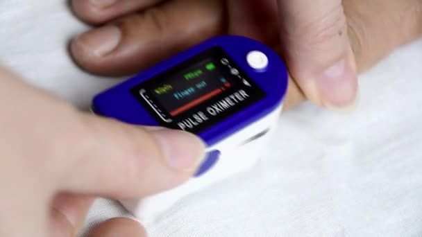 Un homme a mis un oxymètre de pouls sur son doigt et vérifie son rythme cardiaque et la quantité d'oxygène dans son sang. — Video