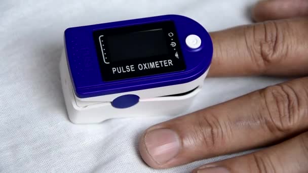 A man put on a pulse oximeter on his finger and checks his heart rate and the amount of oxygen in his blood. — Stock Video