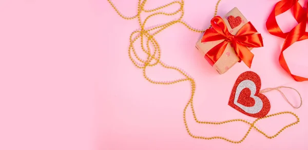 Valentin nap vagy szülinapi ajándék. Valentin napi ajándékok piros papírszívvel, arany gyöngyök rózsaszín háttérrel. Felülnézet. — Stock Fotó