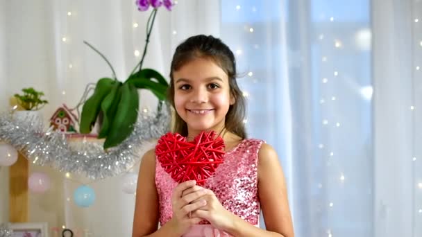 Rødt hjerte tæt på i hænderne på lille mørkt hår smilende pige på Valentinsdag. Langsom bevægelse. – Stock-video