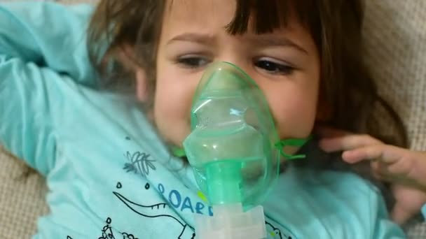 Küçük kız evde nebulizörle solunum yapıyor. Çocuk astım spreyi soluması nebulizatör hastalıklı öksürük konsepti. Hasta bebek evde nebulizör soluyor.. — Stok video