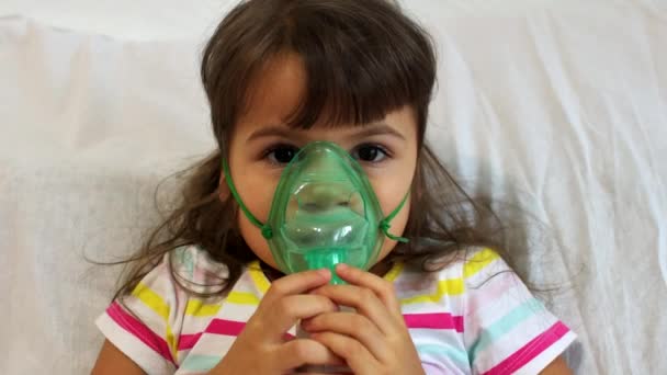 Маленькая девочка делает вдох с помощью ингалятора дома. Ингалятор ингалятора детской астмы больная концепция кашля. Больная девочка дышит в туманность дома. — стоковое видео