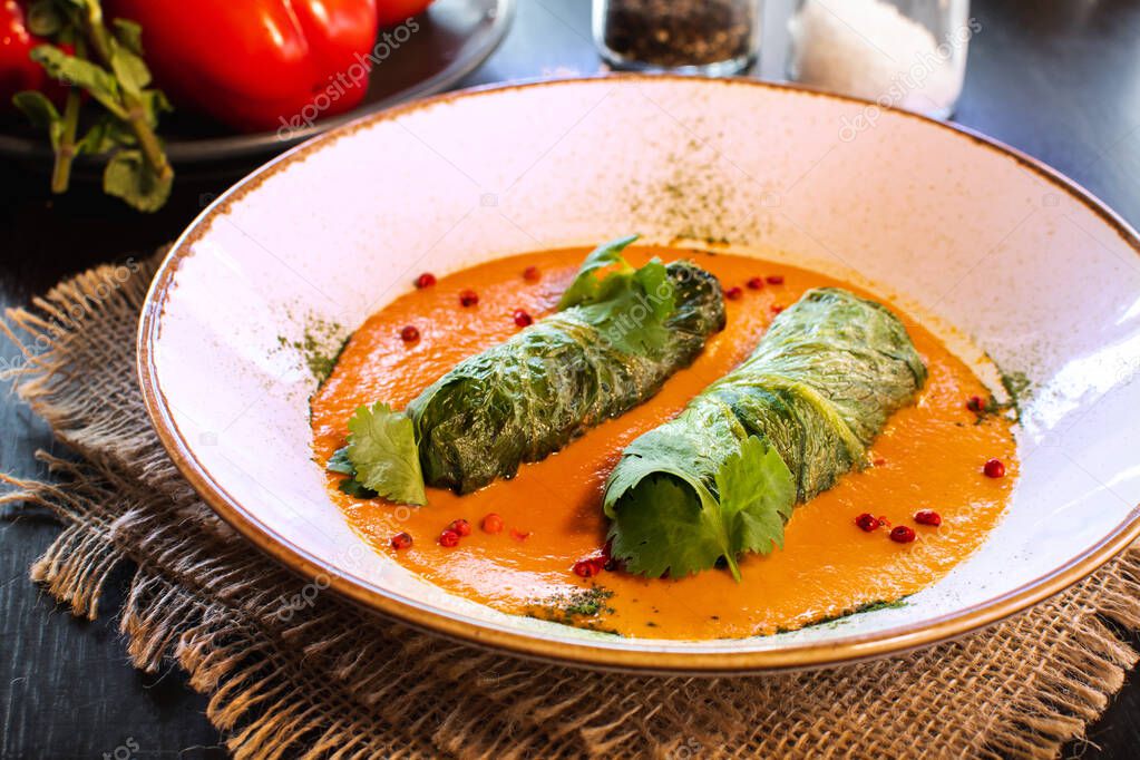 Side view on a dish of eastern european cuisine golubtsy stuffed cabbage leaves with meat or vegetable, with sour cream and carrot.