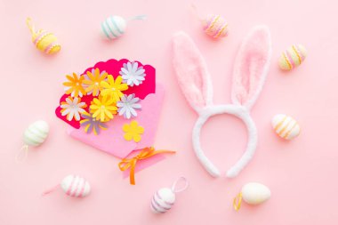 Paskalya gününde pembe arka planda yumurta ve el işi çiçekleri. Baharda Paskalyayı kutluyoruz..