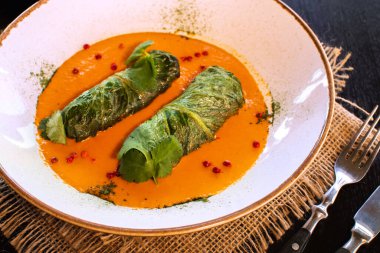 Doğu Avrupa mutfağından bir tabak dolusu dolgun lahana yaprağını et ya da sebzeyle, ekşi krema ve havuçla yan görüyor. Yengemde hizmet ettim.