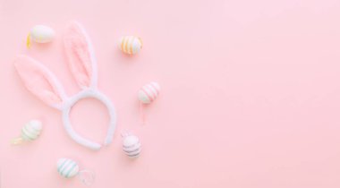 Paskalya günü pembe arka planda tavşan kulakları ve yumurtalar. Baharda Paskalyayı kutluyoruz. Mesaj için yer var. Pankart