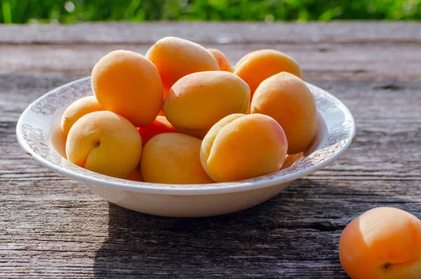 Ripe apricots in a rustic plate on the table, on wooden background. — Stock Photo, Image