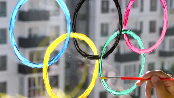 Mädchen, die während der Quarantäne olympische Ringe auf das Fenster malen. Russland. 2. Mai 2021. Moskau. — Stockvideo