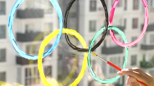 Dívka malovat olympijské prsteny na okno během karantény. Rusko. 2. květen2021. Moskva. — Stock video