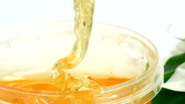 Pasta de açúcar em um jarro transparente em um contexto branco. Um mestre agitar a pasta de açúcar antes de remover o cabelo indesejado. Sugaring. Depilação. Epilação. — Vídeo de Stock