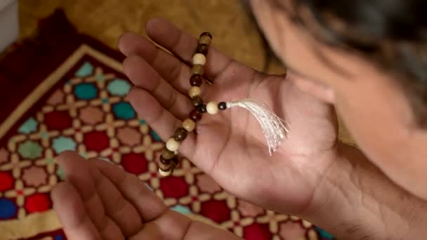 Mans hand with wooden rosary, goes through rosary, blurred background — Stock Video