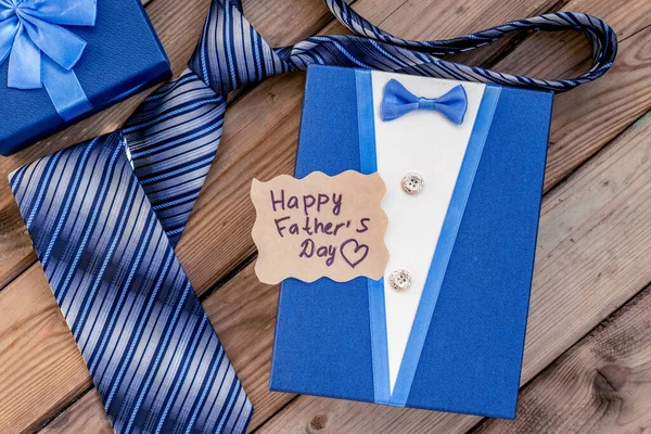 Happy Fathers Day gift blue box with tie on a rustic wood background. Greeting card