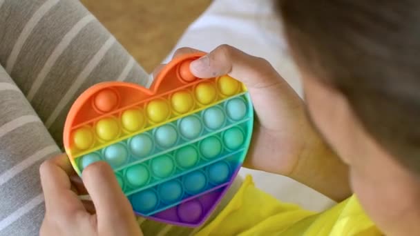 Juguete sensorial antiestrés colorido fidget push pop it en las manos de los niños. — Vídeos de Stock