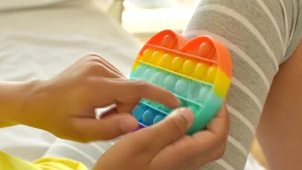 Colorido antistress brinquedo sensorial fidget empurrá-lo pop-lo em mãos de crianças. — Vídeo de Stock